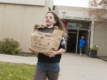 Burke McLeod, a Grade 6 student from Saint Dominic Savio school, runs with a bag of donated groceries to fill a trailer during the annual FCC Drive Away Hunger tour for the Regina Food Bank.