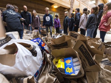 Students and FCC volunteers gather around bags of donated food at W.S. Hawrylak School during the annual FCC Drive Away Hunger tour for the Regina Food Bank.