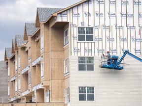 A worker sides a multi-unit housing project under construction in the Greens on Gardiner in Regina on Aug. 14, 2017.