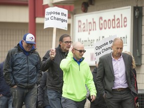 People march and hold signs outside of Ralph Goodale's office to protest proposed changes to the tax code by the federal government. The rally was organized by the Regina and Region Homebuilders Association and the Regina Chamber of Commerce.