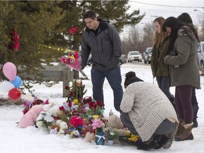 People come to lay a wreath and flowers at a roadside memorial in front of the La Loche Community School, Jan. 27, 2016. Four people, including two brothers, a teacher and an aide were killed last week during the shooting in La Loche.