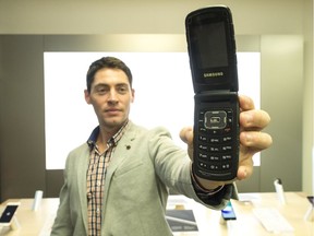 Greg Jacobs, external communications manager for SaskTel, holds up an old flip phone at the Cornwall Centre.