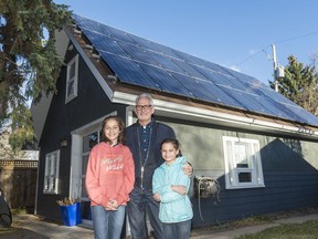 Stephen Hall stands with his daughters Amelia, left, and Penelope, right, in front of solar panels mounted on his home studio on Oct. 23, 2017.