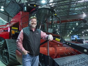 Darryl Priel, territorial sales manager at Young's Equipment, stands in front of a combine during Agribition in the Co-operators Centre.
