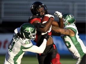 Sure tackling by players such as Ed Gainey, left, and Kacy Rodgers II, right, helped the Saskatchewan Roughriders defeat the Ottawa Redblacks on Sunday. Gainey and Rodgers are shown tackling the Redblacks' Dominique Rhymes.