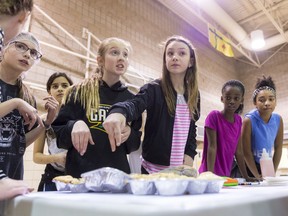 Merceydes Therrien, (centre left) and Victoria Culbert (centre right) negotiate with a customer interested in buying their muffins during the Game of Life at Ecole Monseigneur de Laval School.