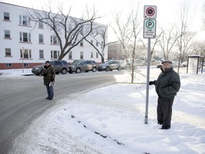 Dawn Ridgway, left, and John Perdicaris hold a tape measure on the southwest corner of 14th Avenue and Halifax Street in Regina. The signpost is approximately five metres from the intersection, far less than the 10 metres the city bylaw allows. Both of them got parking tickets on the street where the vehicles pictured are parked.