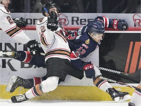 Mark Kastelic of the Calgary Hitmen and Wyatt Sloboshan of the Regina Pats get tied up along the boards in WHL action at the Brandt Centre on Wednesday.