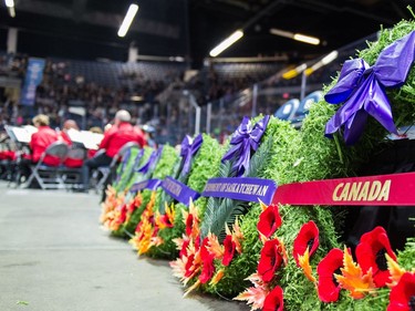 Wreaths are laid out along the floor as a band plays in the background during the Remembrance Day service at the Brandt Centre.