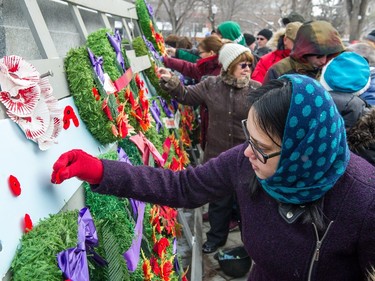 Members of the public pin poppies to the base of the cenotaph during the Remembrance Day service in Victoria Park.