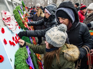 Members of the public pin poppies to the base of the cenotaph during the Remembrance Day service in Victoria Park.