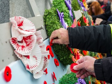 Members of the public pin poppies to the base of the cenotaph during the Remembrance Day service in Victoria Park.