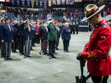 Members of the veterans company, left, salute as an RCMP member, right, stands as a sentry during the Remembrance Day service at the Brandt Centre.