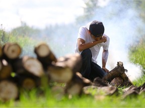 Colten Boushie's brother William Boushie prepares the ceremonial fire before the feast to mark one year since his brother's death outside Chief Glen Keskotagan community centre in Red Pheasant First Nation on August 9, 2017.