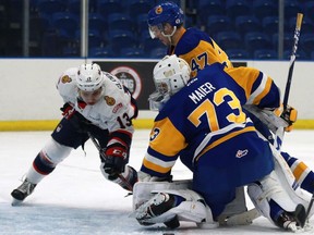 Saskatoon Blades goalie Nolan Maier fights to cover the puck as Regina Pats forward Wyatt Sloboshan pokes away at it during first-period WHL action at SaskTel Centre on Sunday.