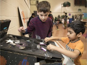 Benjamin Jackson-Reynolds, a grade 8 student at Argyle School, left, shows kindergartener Jwalin Patel how to play his cardboard pinball arcade that student have made. The event is to collect clothing and non-perishable food for the Salvation Army and Regina Food Bank.