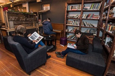 Patrons read in the library of the Artful Dodger while Ben Sefton, centre, plays piano and sings during the last night the business was open.