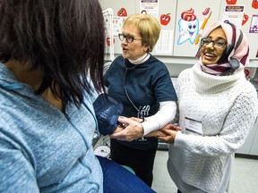 Debbie Rodger, a veteran nurse of 41 years, center, demonstrates how to take a blood pressure reading on Annie Charles, left, with University of Regina health studies student, Saria Jabbar, right, looking on at the Four Directions Health Centre.