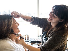 Lori Cappo, left, has her makeup done by Jaie Rombaut, right, during the Help-Potrait Regina event held at the mamaweyatitan centre.