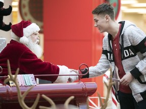 Alex Jones, a Grade 8 student from St. Gregory School, hands Santa Claus a surprise letter of kindness in the Northgate Mall.