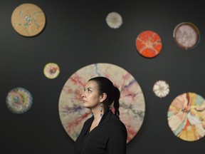 MacKenzie Art Gallery curator Michelle LaVallee sits in front of circle paintings included in the gallery's Alex Janvier exhibit.