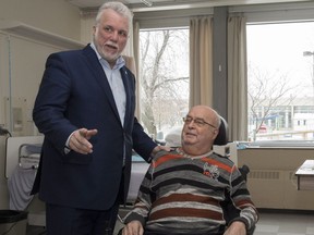 Quebec Premier Philippe Couillard, left, speaks to rehabilitation patient Marinus Pot during a visit at a physical rehabilitation centre in Quebec City on Sunday, December 10, 2017. Couillard announced a government plan on economic inclusion and social participation.