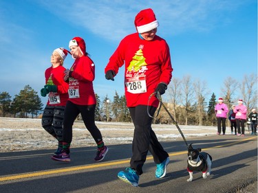 A participant's dog keeps pace as the pair take part in the Santa Shuffle walk/run event that started at the Conexus Arts Centre in Regina on Saturday, Dec. 2, 2017.