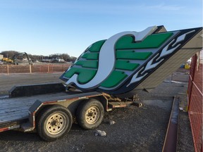 A Saskatchewan Roughriders sign sits on a trailer while machines continue to deconstruct Taylor Field.