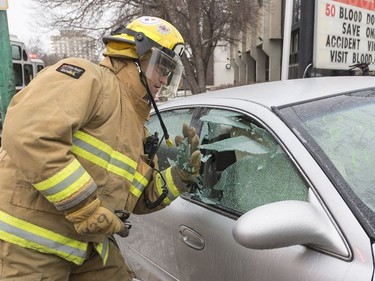 A Regina fire fighter breaks the glass of a car.