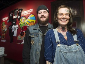 Adrienne Ray, right, and Brennen Garreck of Golden Spider studio stand in front of the logos they made for Rebellion Brewing Company's amber and lentil beers. Rebellion hired the tattoo artists to design art for their cans.