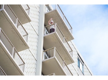 A woman looks on and waves from a balcony high overhead on Broad Street as the Women's March Regina moves along the street on Jan. 20, 2018.