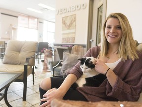 Alex Baylak, owner of VegaBoo Cat Haven, sits on the cat side of the cafe. VegaBoo's cats are from the Regina Humane Society, and people can adopt a cat from the cafe if they meet one they like.