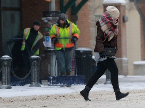 People run through blowing snow while crossing the street downtown Saskatoon, SK on January 30, 2018.