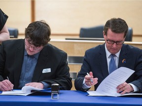 Mayor Michael Fougere, right,  and RM of Sherwood Reeve Jeff Poissant sign a boundary agreement between Regina and the RM of Sherwood at City Hall in Regina.