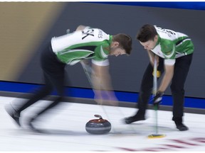 Saskatchewan second Kirk Muyres, left, and lead Dallan Muyres sweep a rock at the Brier.