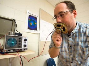 Daniel Dion, a high school science teacher at Ecole Monseigneur de Laval in Regina, demonstrates how he teaches students about electrical currents by using a device called an oscilloscope. In this photo, the device overs a waveform readout of the sound transferred through a speaker which Dion is speaking into.