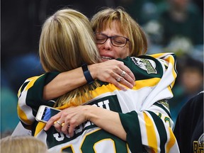 Mourners comfort each other during a vigil at the Elgar Petersen Arena, home of the Humboldt Broncos, to honour the victims of a fatal bus accident, April 8, 2018 in Humboldt, Canada. Mourners in the tiny Canadian town of Humboldt, still struggling to make sense of a devastating tragedy, prepared Sunday for a prayer vigil to honor the victims of the truck-bus crash that killed 15 of their own and shook North American ice hockey.