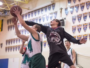 Spencer Peterson, wearing black and grey, stretches to grab a rebound during a basketball game at  Archbishop M.C. O'Neill Catholic High School in Regina.