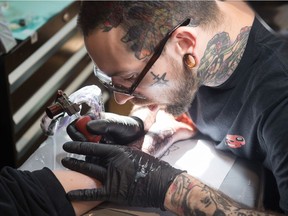 Chris Oakley tattoos Desiree Hilderman, not shown, at the Blacksmith Art Studio on Halifax Street in Regina.