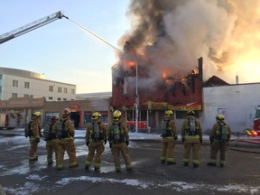 Regina Fire and Protective Services crews stand Wednesday morning as a water cannon tries to contain the blaze at Lang's Cafe on Broad Street.