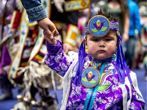 Kaison Obey, a one-year-old powwow dancer from Regina, hangs onto a guiding hand as he makes his way around the dance floor during the Fist Nations University Powwow on April 21, 2018, at the Brandt Centre in Regina.