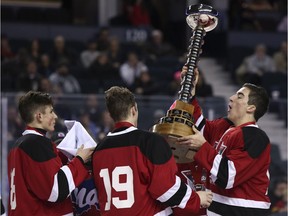 Regina Pat Canadians captain Adam Herold, right, hoists the trophy alongside teammates Matt Culling, 18, and Taylor Halbgewachs, 19, after the team won the Mac's midget hockey tournament in Calgary on Jan. 1.