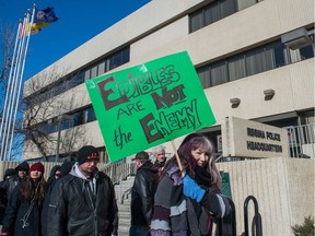 Karla Weber holds up a sign as people march in front of the Regina police station during a demonstration meant to protest the raid of local marijuana dispensaries.