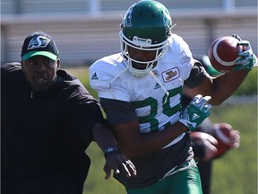 Receivers coach Travis Moore (left) helps Duron Carter (89) wth a drill during the Riders' training camp in Saskatoon.