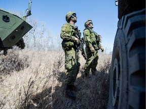 Sgt Steven Arens of the Saskatchewan Dragoons, right, looks over his crew's new Tactical Armoured Patrol Vehicle as a simulation unfolds during Exercise ARMOURED BISON 2018 at Canadian Forces Detachment Dundurn, northwest of the town of Dundurn, Saskatchewan.