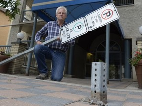 Bill Bolstad poses in front of his condo building in Regina on Aug. 16, 2015. Bolstad holds a sign, to which only hours before his bike was locked. Someone apparently unbolted the sign from its base (foreground), and made away with the bike in broad daylight.