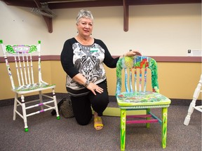Artist Janice Moser kneels next to a chair she painted. The work was part of a collection which is to be auctioned off in support of the Stephen Lewis Foundation's Grandmothers to Grandmothers Campaign. This campaign supports grandmothers in sub-Saharan Africa raising their grandchildren who have been orphaned by AIDS.