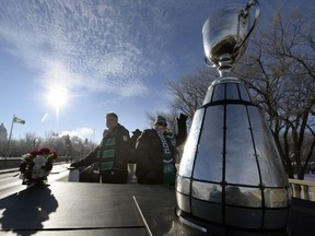 Roughriders president-CEO Jim Hopson, right, and team chairman Roger Brandvold accompany the Grey Cup on a horse-drawn wagon during a victory parade in 2013
