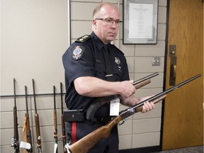 Deputy Chief Dean Rae, of the Regina Police Service, holds both a sawed off shotgun and regular shotgun as part of the weapons turned in during a province wide gun amnesty.