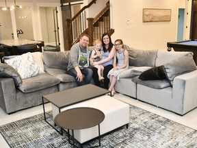 Dwayne Prystupa, from left, and wife Kristen sit with their daughters Piper (centre-left) and Lexa Barous in their new home, the grand prize of the Hospitals of Regina lottery.